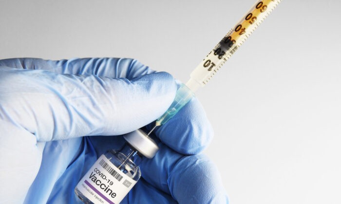 Шприц, вставленный во флакон с вакциной COVID-19. Robert Avgustin/Shutterstock | Epoch Times Россия