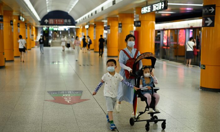 Женщина идёт по станции метро с двумя детьми в Пекине 5 июля 2022 года. (WANG ZHAO/AFP via Getty Images) | Epoch Times Россия