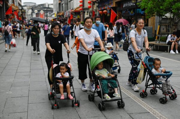 Женщины везут детские коляски по деловой улице в Пекине 13 июля 2021 года. (Wang Zhao/AFP via Getty Images)