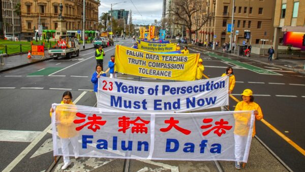 Последователи Фалунь Дафа держат транспаранты, проходя по улице Спринг, Мельбурн, Австралия, во время марша памяти 9 июля 2022 года. (Chen Ming/Epoch Times)