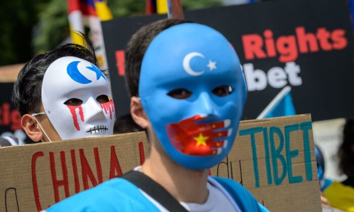 Около 200 уйгурских активистов в масках на акции протеста против зимних Олимпийских игр 2022 года в Пекине 23 июня 2021 года. Фото: Fabrice COFFRINI / AFP
 | Epoch Times Россия
