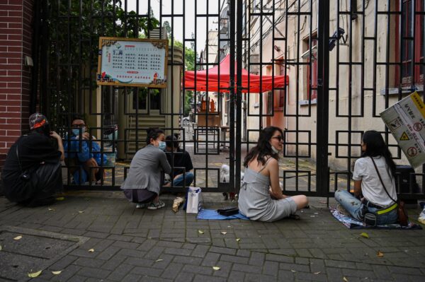 Люди с пропуском на два-три часа из своих жилых комплексов разговаривают с запертыми жителями во время блокировки COVID-19 в районе Цзинъань в Шанхае 27 мая 2022 года. (Hector Retamal/AFP via Getty Images)