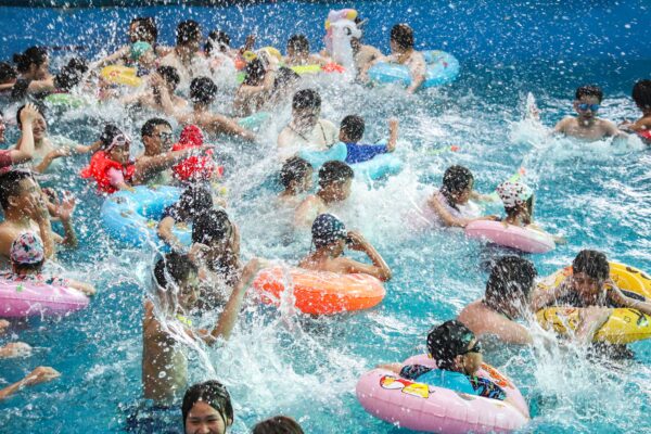 Люди охлаждаются в бассейне, спасаясь от жаркой погоды в аквапарке в Хуайане восточной китайской провинции Цзянсу, 18 июля 2022 года. (STR/AFP via Getty Images)