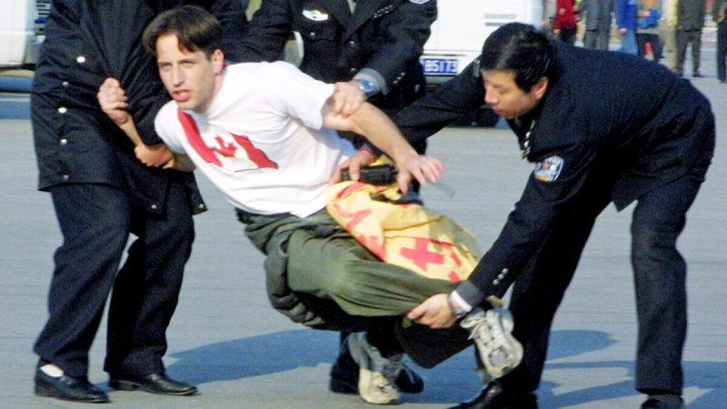 Китайские полицейские забирают канадского практикующего Фалуньгун во время того, как он участвовал в мирной акции протеста на площади Тяньаньмэнь в ноябре 2001 года. Фото: Нг Хан Гуань/AP | Epoch Times Россия