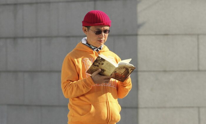 Сяо Цзяньхуа, канадский миллиардер китайского происхождения, читает книгу возле Международного финансового центра в Гонконге в декабре 2013 года. (Next Magazine/AP Photo)
 | Epoch Times Россия