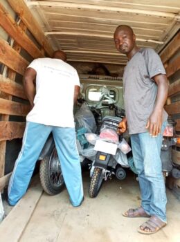 Ерима Тимоти (справа) стоит рядом с мотоциклами, переданными террористам в качестве части выкупа за 15 человек, похищенных в городе Касан-Коги в феврале. (Предоставлено Еримой Тимоти)