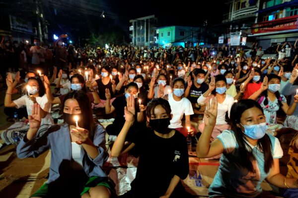 Демонстранты против переворота приветствуют друг друга трёхпалым жестом во время ночного митинга при свечах в Янгоне, Мьяниа, 14 марта 2021 года. (AP Photo)