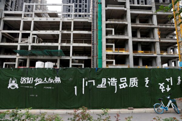 Облупившийся логотип Evergrande Oasis, жилого комплекса, разработанного Evergrande Group, возле строительной площадки с недостроенными жилыми зданиями в Лояне, Китай, 16 сентября 2021 года. (Carlos Garcia Rawlins/Reuters)