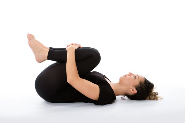 Поза йоги Апанасана (лёжа — колени у груди). Фото:  Wuju Planet/Shutterstock