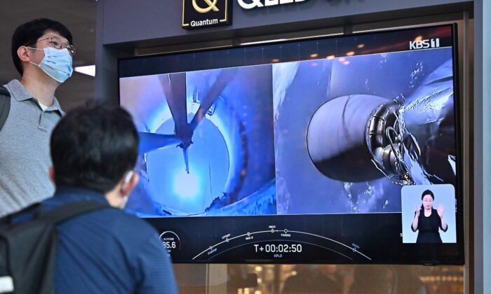 Люди смотрят на экран телевизора, показывающего прямую трансляцию запуска ракеты SpaceX Falcon 9 с первым южнокорейским лунным орбитальным аппаратом Danuri на борту с мыса Канаверал во Флориде, на железнодорожной станции в Сеуле, Южная Корея, 5 августа 2022 года. (Jung Yeon-je/AFP via Getty Images) | Epoch Times Россия