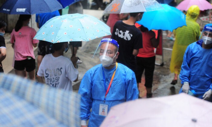 Медицинский работник наблюдает, как жители и туристы выстраиваются в очередь для прохождения тестов на COVID-19 в Санье, провинция Хайнань на юге Китая, 8 августа 2022 года. (STR/AFP via Getty Images)
 | Epoch Times Россия