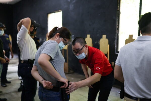 Инструктор проверяет, правильно ли размещён пистолет стажёра в кобуре во время учебного занятия на стрельбище компании по обучению боевым навыкам Polar Light в Нью-Тайбэе, Тайвань, 29 мая 2022 года. (Reuters/Ann Wang)