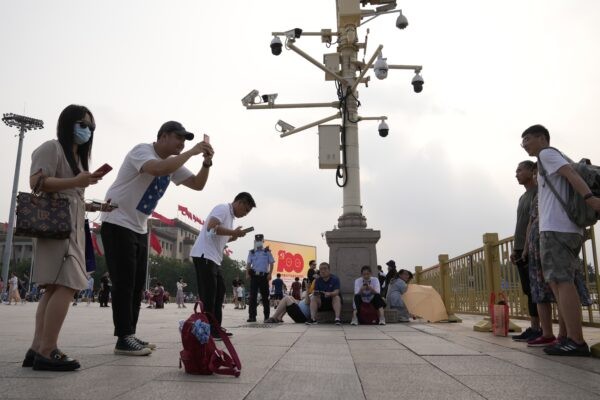 Посетители фотографируются возле камер наблюдения на площади Тяньаньмэнь в Пекине, 15 июля 2021 года. (Ng Han Guan/AP Photo)