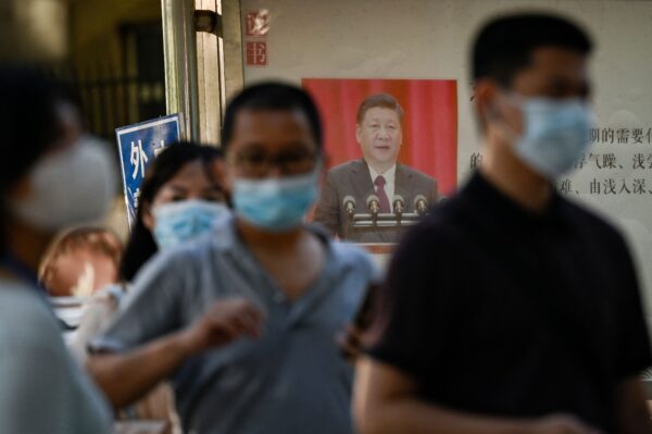 Люди стоят в очереди, чтобы пройти тест на COVID-19, рядом с пропагандистским плакатом с изображением лидера Китая Си Цзиньпина в Пекине 31 августа 2022 года. (Jade Gao/AFP via Getty Images)