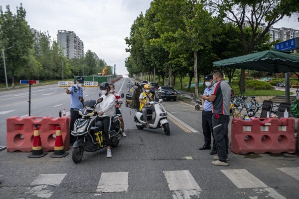 Полицейские проверяют данные людей на блокпосте из-за вспышки вируса COVID-19 в Чэнду, юго-западная провинция Сычуань, Китай, 1 сентября 2022 года. (CNS/AFP via Getty Images)