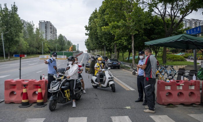 Полицейские проверяют информацию о людях на блокпосте 1 сентября 2022 года из-за ограничений, связанных со вспышкой COVID-19 в Чэнду, юго-западная провинция Сычуань, Китай. (CNS/AFP через Getty Images)
 | Epoch Times Россия