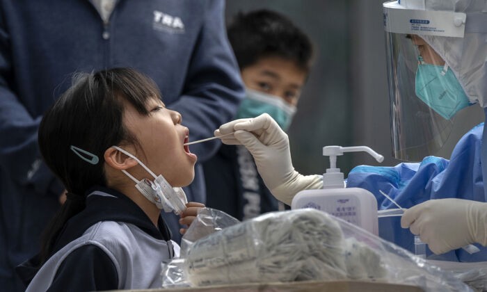 Медицинский работник проводит тест на нуклеиновую кислоту молодой девушке в пункте тестирования на COVID-19 в Пекине, Китай, 29 апреля 2022 года. (Kevin Frayer/Getty Images)
 | Epoch Times Россия