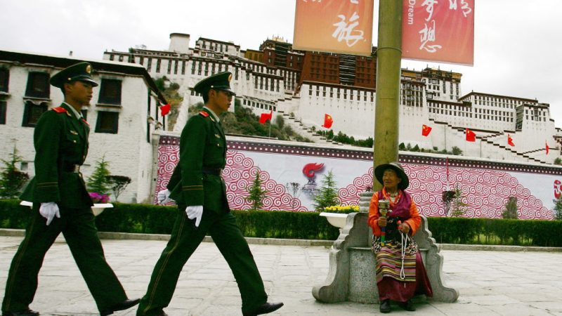 Тибетец наблюдает, как китайские полицейские патрулируют дворец Потала в Лхасе, Тибет, 20 июня 2008 г. (Guang Niu/Getty Images) | Epoch Times Россия