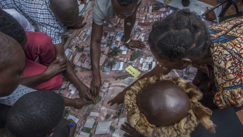 Люди разглядывают аэрофотоснимок, сделанный с помощью камеры беспилотника во время картографирования очагов холеры, организованного и финансируемого ЮНИСЕФ в Малави, в Ликуни, недалеко от Лилонгве, Малави, 27 января 2018 года. Фото: (Amos Gumulira/AFP via Getty Images) | Epoch Times Россия
