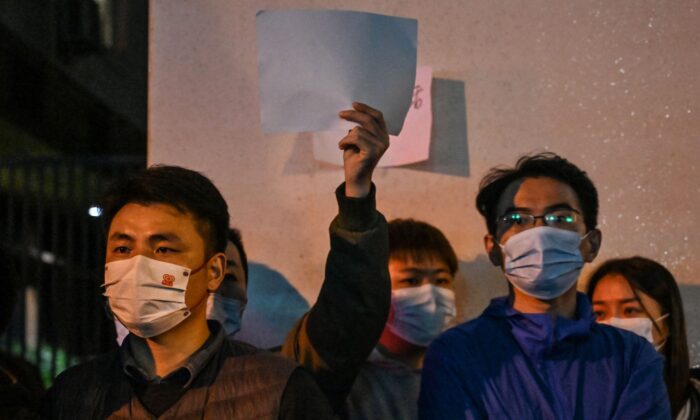 Люди держат чистые листы бумаги в знак протеста в Шанхае 27 ноября 2022 года, где накануне прошли акции протеста против политики «нулевого COVID» Китая после смертельного пожара в Урумчи, столице региона Синьцзян. Фото: Hector Retamal/AFP/Getty Images | Epoch Times Россия