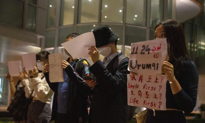 Протестующие держат в руках белые листы, некоторые из которых написаны в память о смертоносном пожаре в Урумчи 24 ноября, во время собрания в Университете Гонконга в Гонконге 29 ноября 2022 года. (AP Photo/Bertha Wang) | Epoch Times Россия