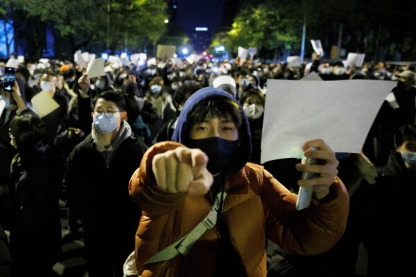 Люди держат белые листы бумаги во время демонстрации в Пекине 27 ноября 2022 года. (Thomas Peter/Reuters)