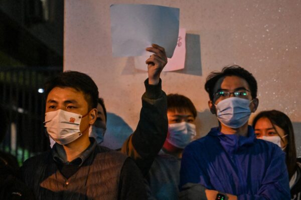 Люди, держащие чистые листы бумаги в знак протеста, на улице в Шанхае 27 ноября 2022 года, где накануне прошли демонстрации против политики «нулевого COVID». Фото: Hector Retamal/AFP/Getty Images