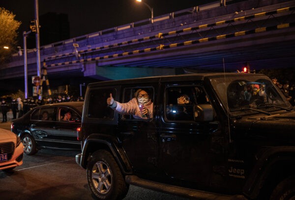 Люди поддерживают протестующих против строгих мер Китая по борьбе с «нулевым COVID» в Пекине 27 ноября 2022 года. (Kevin Frayer/Getty Images)