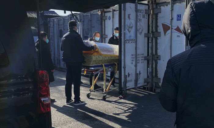 Гроб загружают с катафалка в контейнер для хранения в крематории и похоронном бюро Дунцзяо, одном из нескольких в городе, который занимается случаями COVID-19 в Пекине, Китай, 18 декабря 2022 года. (Getty Images) | Epoch Times Россия