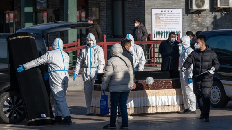Рабочие в защитном снаряжении обрабатывают гроб в похоронном бюро «Дунцзяо», которое предназначено для смертельных случаев COVID-19, в Пекине 19 декабря 2022 года. (BloombergviaGettyImages) | Epoch Times Россия