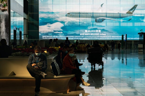 Путешественники сидят в зале прибытия международного аэропорта Гонконга, 30 декабря 2022 года. (Anthony Kwan/Getty Images)