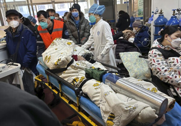 Пациента, подключённого к баллону с кислородом, везут на каталке в переполненное отделение неотложной помощи больницы в Пекине 2 января 2023 года. (Getty Images)
