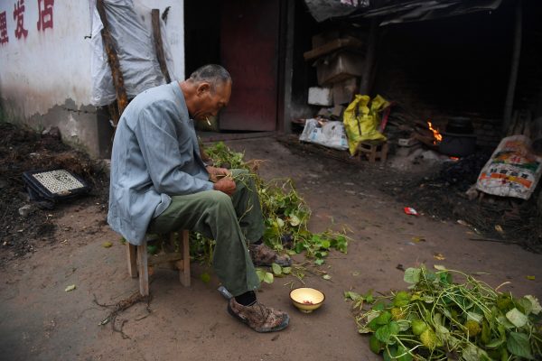 Мужчина готовит бобы возле своего дома в деревне недалеко от реки Хуанхэ в уезде Ланкао, провинция Хэнань, 28 сентября 2017 года. (Greg Baker/AFP/Getty Images)