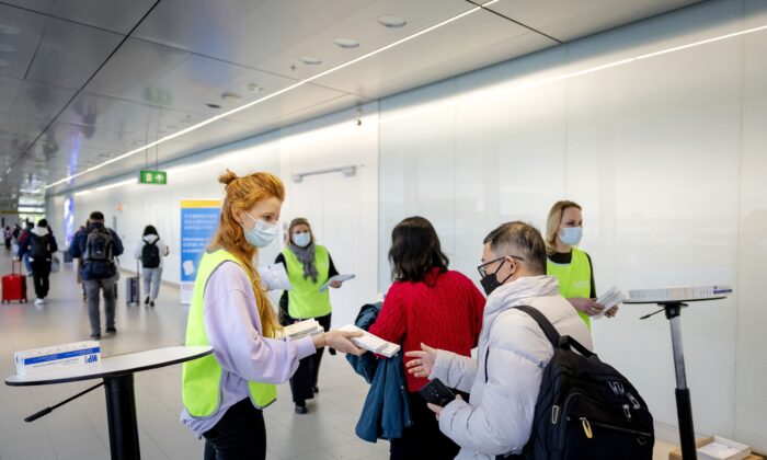 Сотрудник голландской муниципальной службы здравоохранения (GGD) раздаёт бесплатные наборы для самотестирования на COVID-19 путешественникам, прибывающим из Китая, в аэропорту Схипхол, Нидерланды, 4 января 2023 года. (Robin van Lonkhuijsen/ANP/AFP via Getty Images)
 | Epoch Times Россия