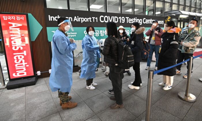 Медицинские работники сопровождают туристов из Китая перед центром тестирования COVID-19 в международном аэропорту Инчхон к западу от Сеула, 3 января 2023 года. (Jung Yeon-je/AFP via Getty Images) | Epoch Times Россия