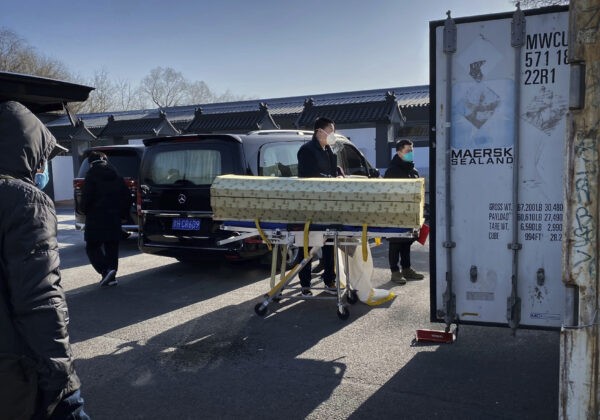 Гроб загружают с катафалка в контейнер для хранения в крематории и похоронном бюро Дунцзяо в Пекине, 18 декабря 2022 года. (Getty Images)