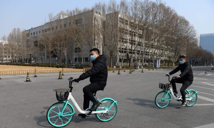 Двое мужчин едут на велосипедах по пустынной территории Университета Цинхуа в Пекине 28 февраля 2020 года. (Greg Baker/AFP via Getty Images)
 | Epoch Times Россия