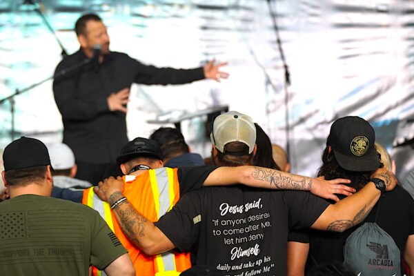 Трое мужчин обнимаются, когда пастор из Теннесси Марио Мурильо читает свою проповедь в Бейкерсфилде, Калифорния, 12 марта 2023 года. (Allan Stein/The Epoch Times)