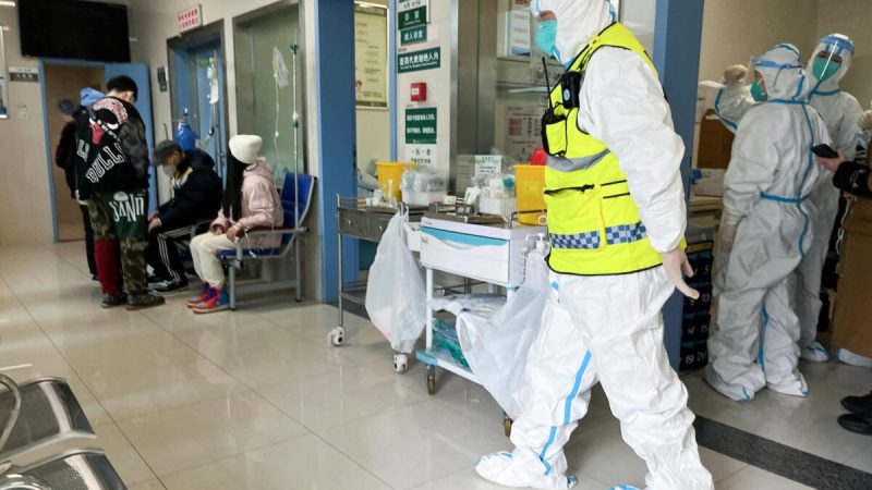 Сотрудник службы безопасности в защитном костюме наблюдает за тем, как медицинские работники обслуживают пациентов в больнице Тунцзи для больных COVID-19, Ухань, провинция Хубэй, Китай, 1 января 2023 года. (Reuters)
 | Epoch Times Россия