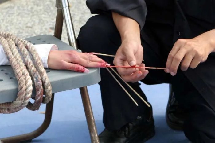 Реконструкция пытки зубочистками, воткнутыми под ногти. (Courtesy of Minghui.org)
