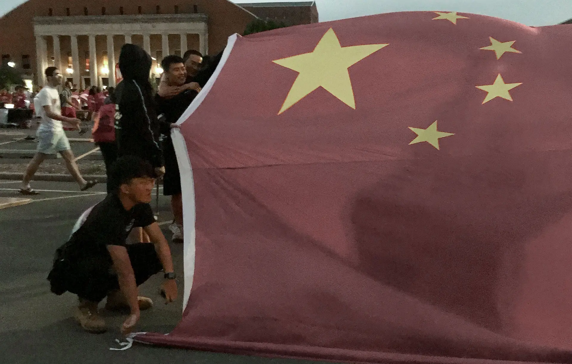 (Справа) Группа китайских студентов заблокировала стенд студенческого клуба Вана гигантским китайским национальным флагом на фестивале в кампусе в августе 2019 года. (Courtesy of Wang Jianghao) «Вам не избежать его когтей»: длинная рука Пекина нацелена на студентов
