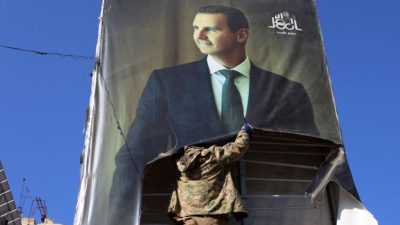 Повстанцы срывают портреты президента Сирии Башара аль-Асада в Алеппо после захвата города. (MOHAMMED AL-RIFAI/AFP via Getty Images) 
