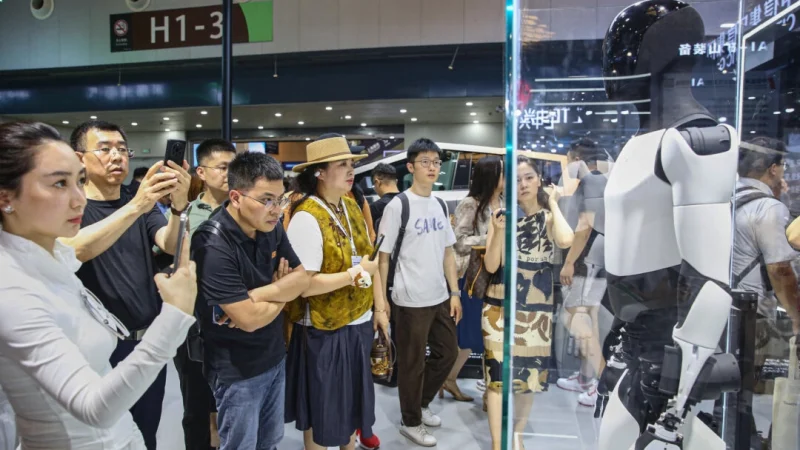 Посетители осматривают гуманоидного робота Tesla Optimus в Шанхае, Китай, 5 июля 2024 года. (STR/AFP через Getty Images) | Epoch Times Россия