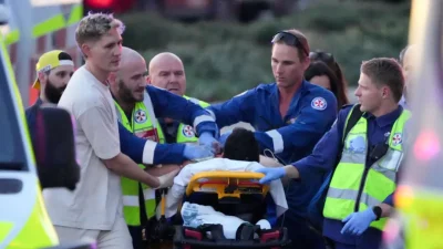 Сотрудники экстренных служб перевозят человека на носилках после сообщения о стрельбе на пляже Бонди в Сиднее, воскресенье, 14 декабря 2025 года. (AP Photo/Mark Baker)