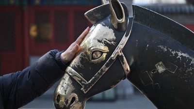 Женщина гладит голову статуи лошади в храме Пекина во время празднования Китайского Нового года 2026.