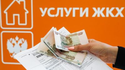 Рука держит квитанцию по оплате услуг ЖКХ и российские рубли.