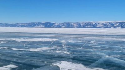 Прозрачный лед озера Байкал с трещинами на официальном маршруте ледовой дороги до острова Ольхон.