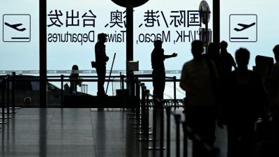 Силуэты пассажиров и охраны на фоне табло вылетов в международном аэропорту Пекина, символизирующие ограничение выезда для китайских чиновников.