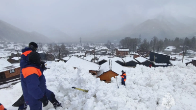 Спасатели МЧС на месте схода лавины в поселке Архыз: поврежденные снежной массой деревянные дома и автомобили.