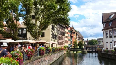 Фахверковые дома и цветочные террасы кафе вдоль речного канала в историческом районе Пти-Франс, Страсбург.